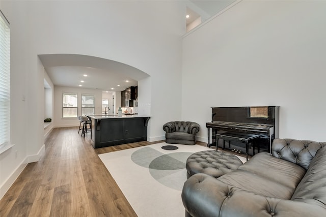 living room featuring sink, light wood-type flooring, and a high ceiling