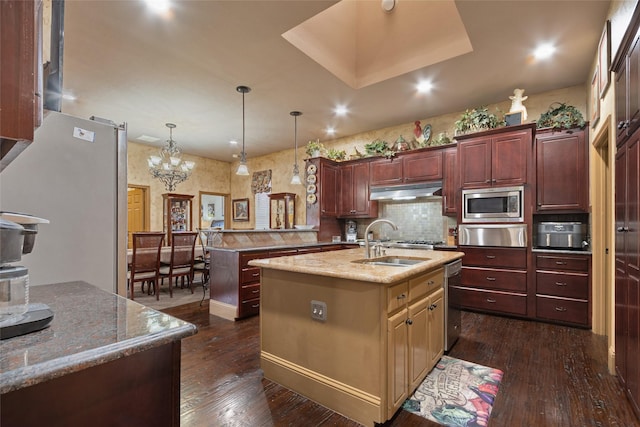 kitchen featuring an inviting chandelier, an island with sink, stainless steel appliances, decorative light fixtures, and sink