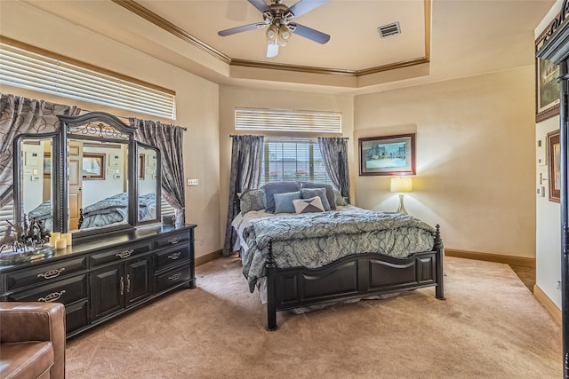 bedroom featuring ceiling fan, a tray ceiling, ornamental molding, and light carpet