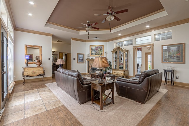 living room with ceiling fan, a tray ceiling, ornamental molding, and hardwood / wood-style flooring