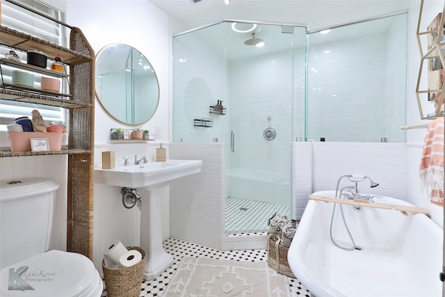 bathroom with a shower with door, sink, toilet, and tile walls