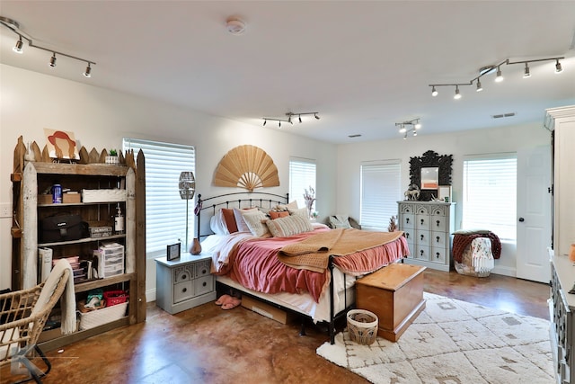 bedroom featuring concrete flooring and rail lighting