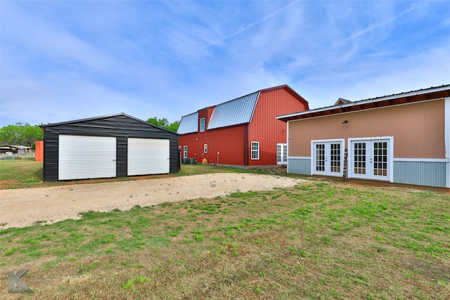 view of yard with a garage, an outdoor structure, and french doors