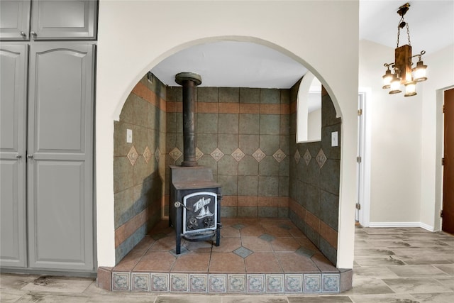 interior space featuring light tile floors, decorative light fixtures, gray cabinetry, tile walls, and a wood stove