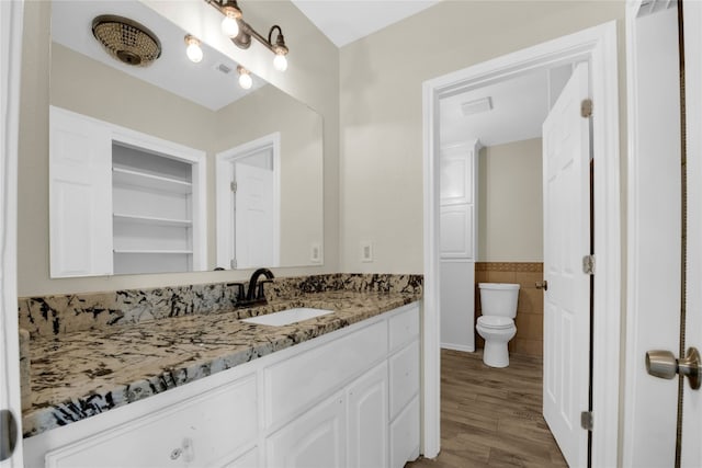 bathroom with oversized vanity, toilet, and wood-type flooring