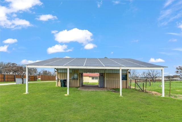 rear view of house featuring solar panels and a yard