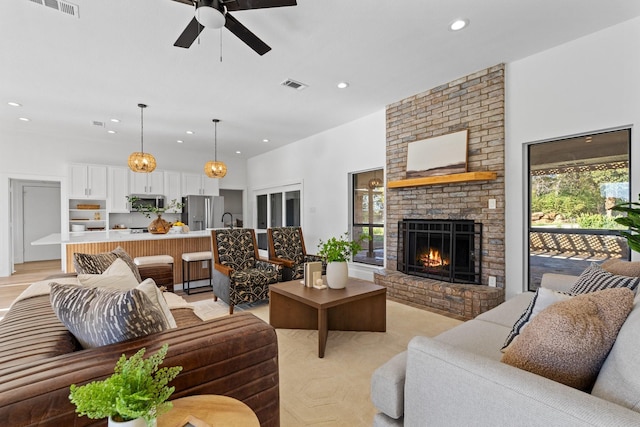 living room featuring a brick fireplace, sink, and ceiling fan