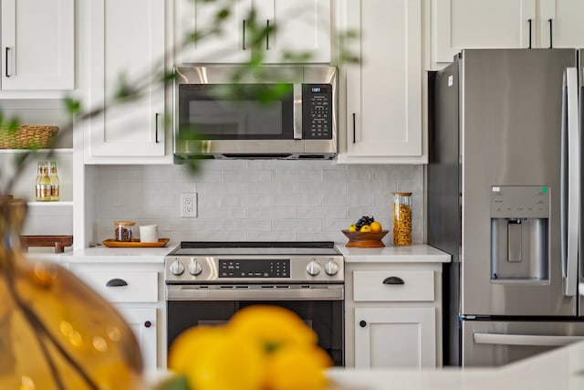 kitchen with decorative backsplash, white cabinets, and appliances with stainless steel finishes