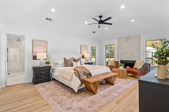 bedroom featuring connected bathroom, light hardwood / wood-style floors, multiple windows, and lofted ceiling