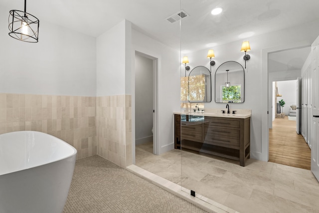 bathroom with toilet, vanity, a tub to relax in, and tile patterned floors