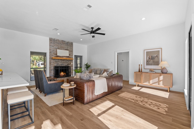 living room with a fireplace, light hardwood / wood-style floors, and ceiling fan