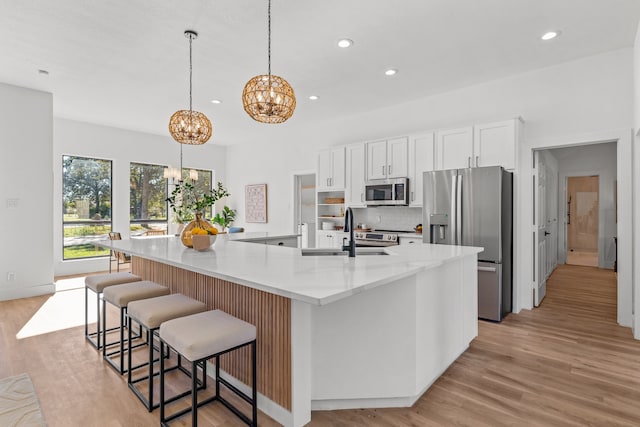 kitchen with sink, pendant lighting, a spacious island, white cabinets, and appliances with stainless steel finishes