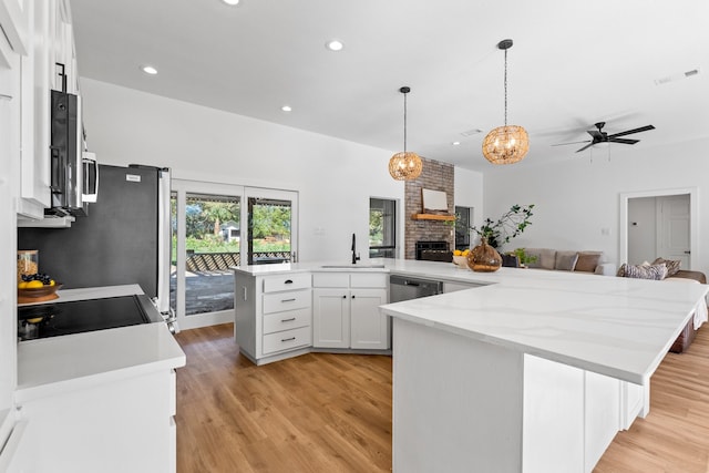 kitchen with white cabinets, sink, light wood-type flooring, decorative light fixtures, and a breakfast bar area