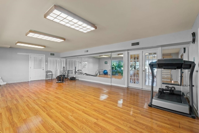 workout area featuring french doors and light wood-type flooring