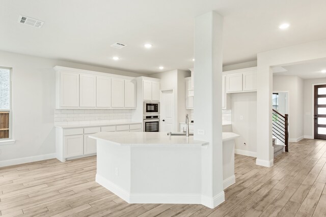 kitchen featuring a sink, visible vents, stainless steel oven, built in microwave, and tasteful backsplash