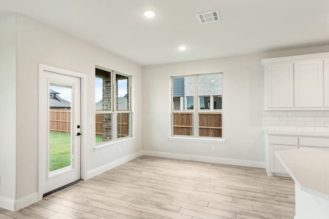 unfurnished dining area featuring light wood finished floors, baseboards, visible vents, and recessed lighting