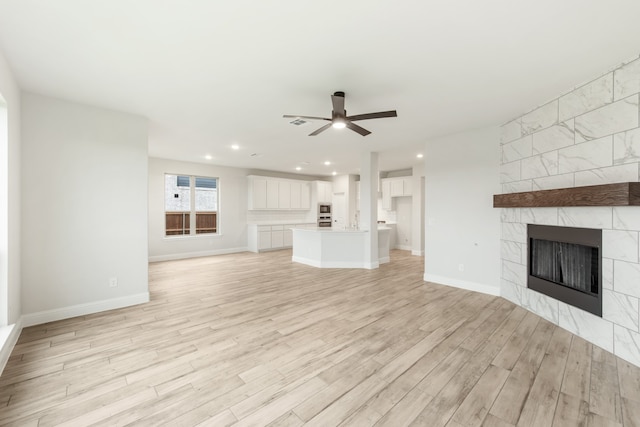 unfurnished living room with baseboards, a tiled fireplace, ceiling fan, light wood-style floors, and recessed lighting