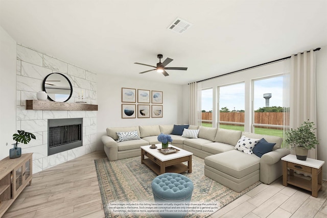 living room featuring wood finished floors, a high end fireplace, visible vents, and a ceiling fan