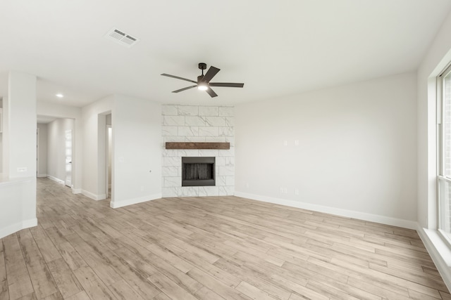 unfurnished living room with a fireplace, visible vents, baseboards, a ceiling fan, and light wood-type flooring