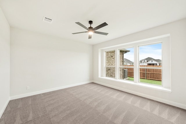 carpeted empty room with visible vents, ceiling fan, and baseboards