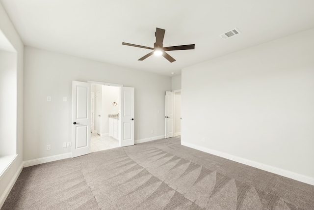 unfurnished bedroom with carpet floors, visible vents, ensuite bath, and baseboards