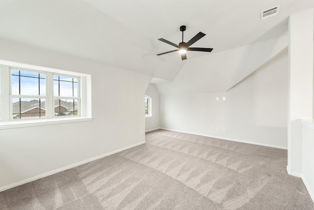 carpeted spare room with a ceiling fan, lofted ceiling, visible vents, and baseboards