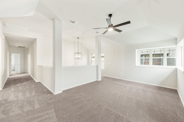 carpeted empty room with lofted ceiling, baseboards, visible vents, and ceiling fan with notable chandelier