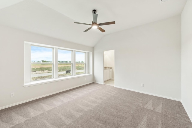 empty room with light colored carpet, vaulted ceiling, baseboards, and ceiling fan