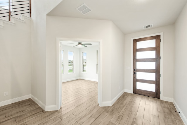 entryway with light wood finished floors, stairway, and visible vents