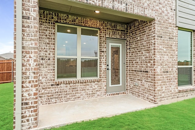 doorway to property with fence and brick siding