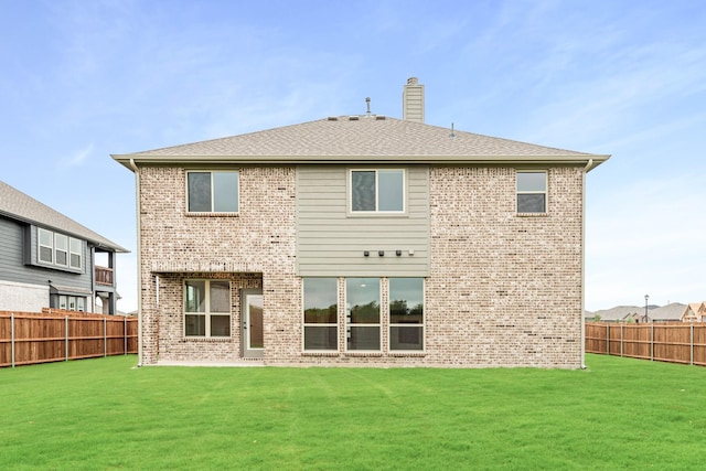 rear view of house featuring a yard, brick siding, a chimney, and a fenced backyard