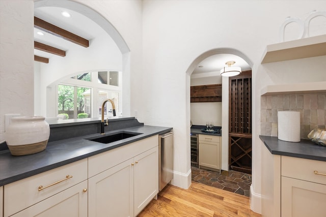 kitchen featuring light wood-type flooring, wine cooler, beamed ceiling, sink, and stainless steel dishwasher