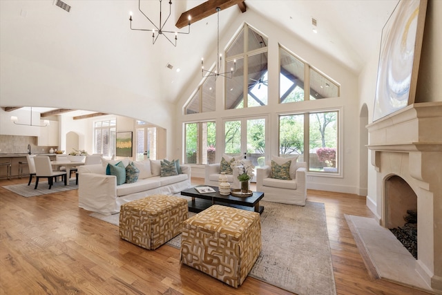 living room with a notable chandelier, a healthy amount of sunlight, and high vaulted ceiling