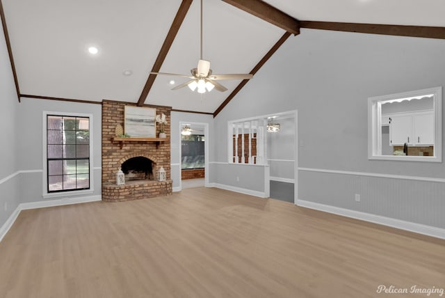 unfurnished living room featuring beam ceiling, a brick fireplace, light wood-type flooring, and ceiling fan