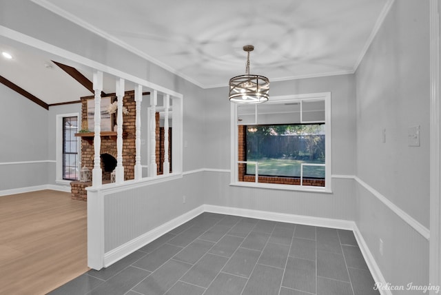 empty room featuring crown molding, vaulted ceiling, a large fireplace, and an inviting chandelier