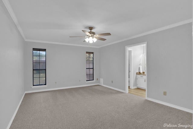 carpeted spare room featuring ceiling fan, ornamental molding, and plenty of natural light