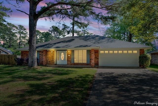 ranch-style house with a garage and a yard