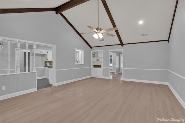 unfurnished living room with beamed ceiling, ceiling fan, built in features, and light wood-type flooring