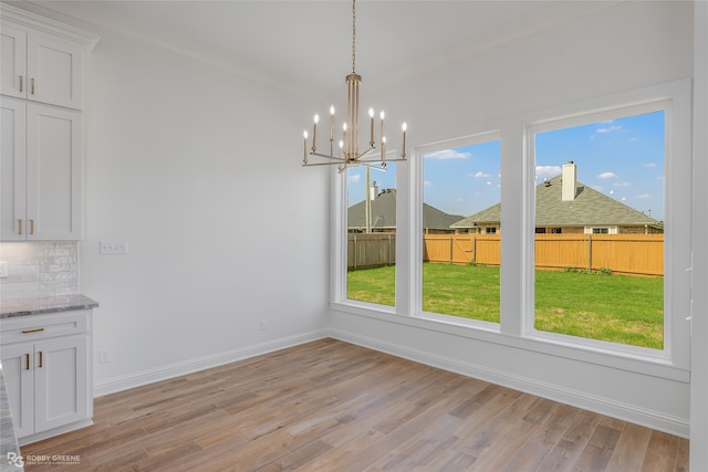 unfurnished dining area featuring light hardwood / wood-style flooring, plenty of natural light, and a chandelier