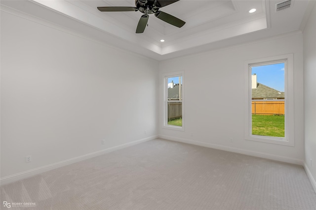 spare room featuring a tray ceiling, visible vents, light carpet, and baseboards