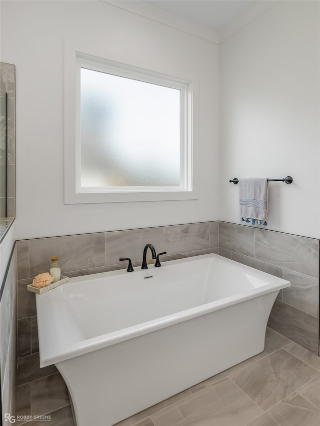 bathroom featuring tile patterned floors, tile walls, a washtub, and a wealth of natural light