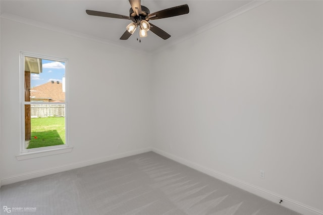 carpeted spare room with ornamental molding, baseboards, and a ceiling fan