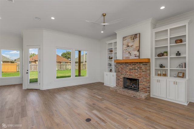 unfurnished living room featuring ornamental molding, light hardwood / wood-style flooring, a fireplace, and built in shelves