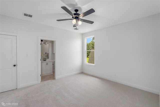 unfurnished bedroom with connected bathroom, light colored carpet, and ceiling fan