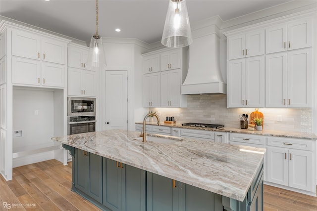 kitchen featuring a center island with sink, backsplash, light hardwood / wood-style flooring, and sink