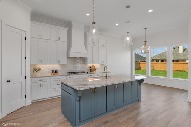 kitchen featuring premium range hood, a sink, white cabinetry, tasteful backsplash, and stainless steel gas stovetop