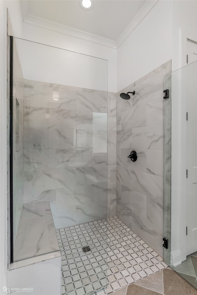 bathroom featuring tiled shower, crown molding, and tile patterned flooring