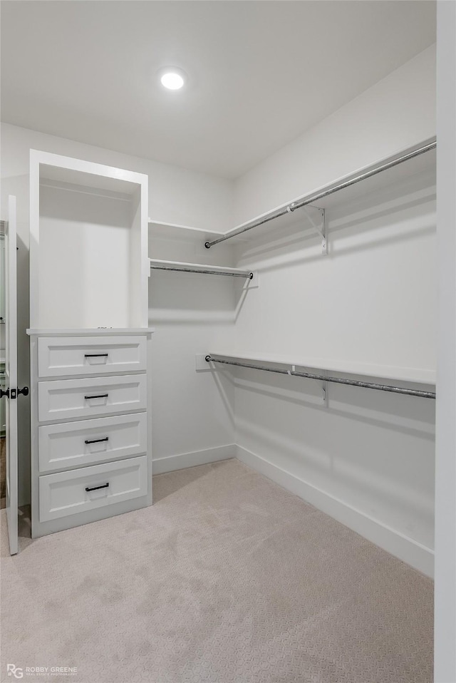 walk in closet featuring light colored carpet