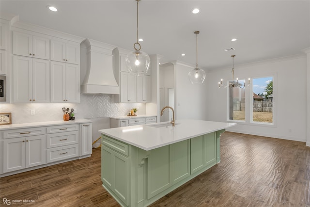 kitchen with custom exhaust hood, tasteful backsplash, dark hardwood / wood-style flooring, an island with sink, and green cabinetry