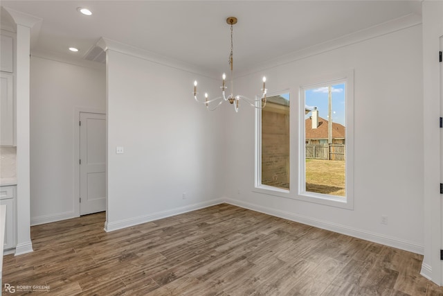 unfurnished dining area featuring a notable chandelier, baseboards, and wood finished floors